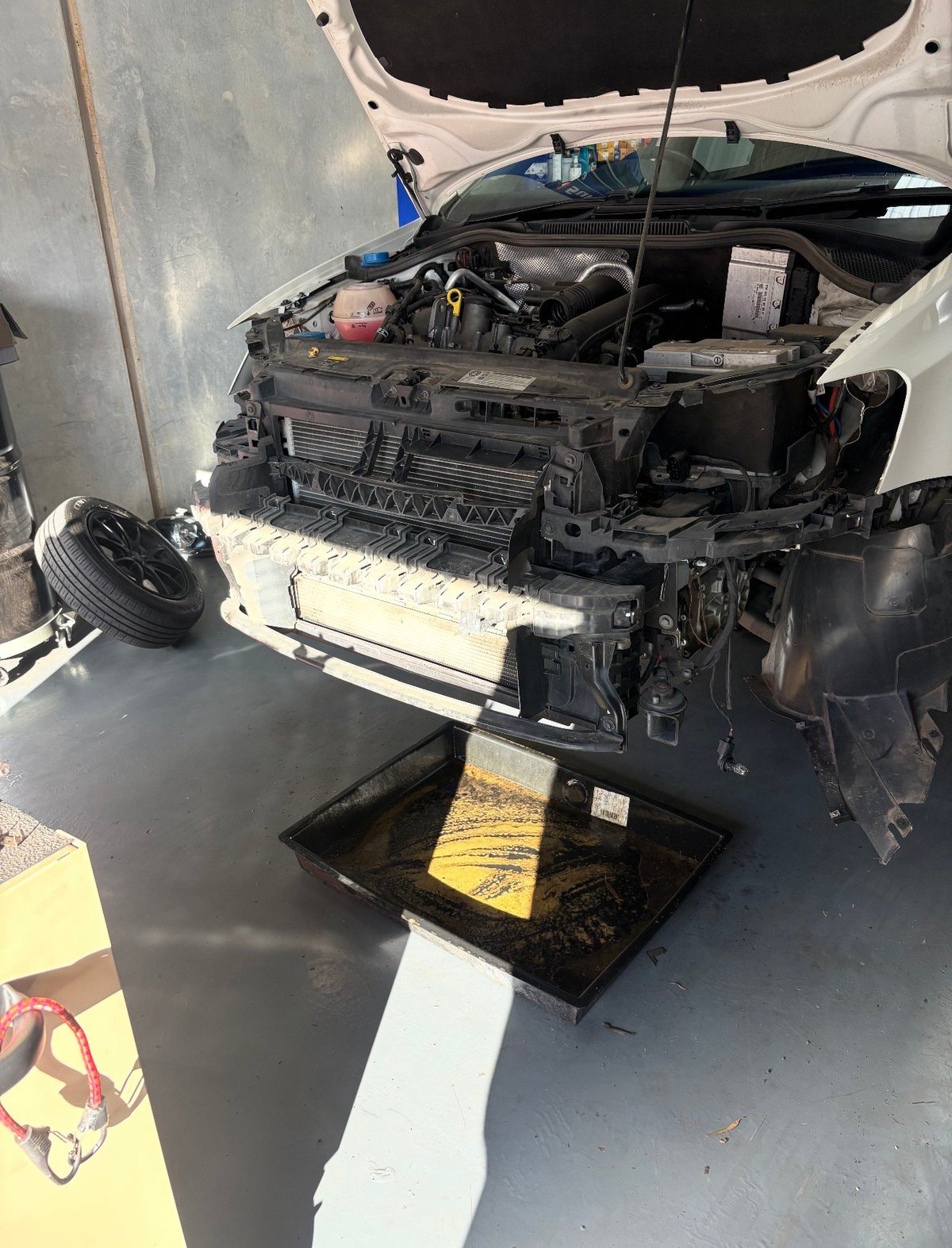 Open car hood showing engine and removed radiator on black stand in garage